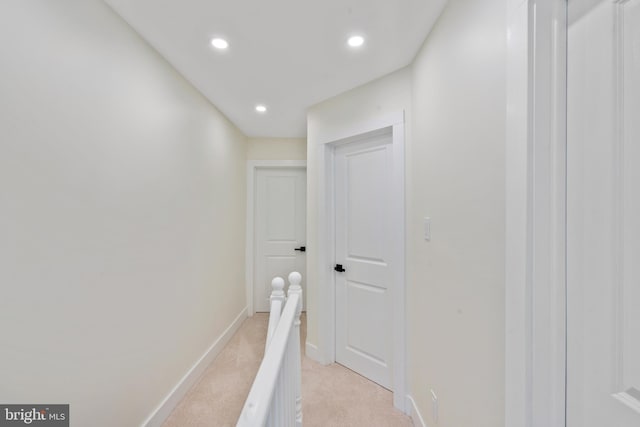 hall featuring recessed lighting, light colored carpet, baseboards, and an upstairs landing