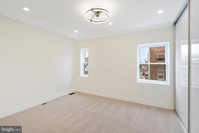 unfurnished room with recessed lighting, baseboards, light carpet, and visible vents