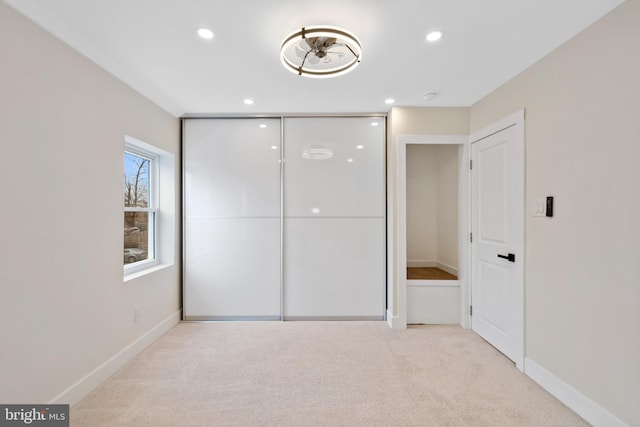 unfurnished bedroom with a closet, carpet flooring, recessed lighting, and baseboards