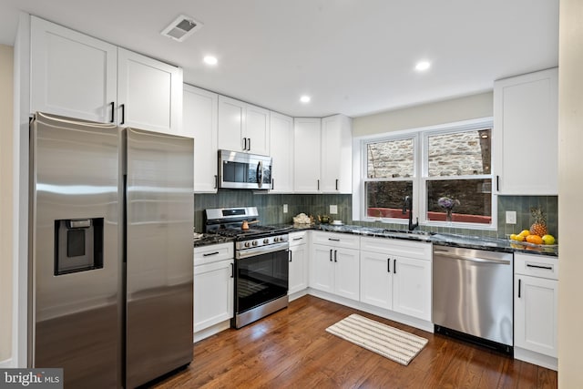 kitchen with dark wood-style floors, visible vents, a sink, appliances with stainless steel finishes, and white cabinetry