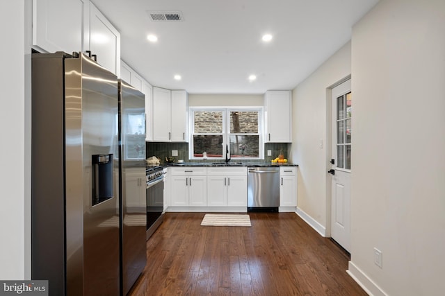 kitchen featuring decorative backsplash, dark countertops, appliances with stainless steel finishes, and white cabinetry