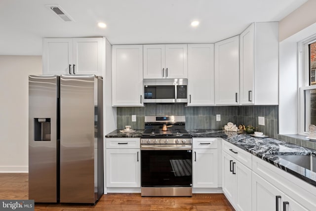 kitchen with tasteful backsplash, visible vents, light wood-style flooring, white cabinets, and stainless steel appliances