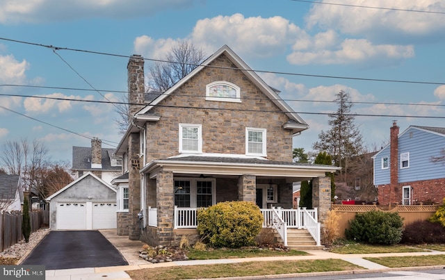 view of front of house featuring fence, covered porch, a chimney, a garage, and an outdoor structure