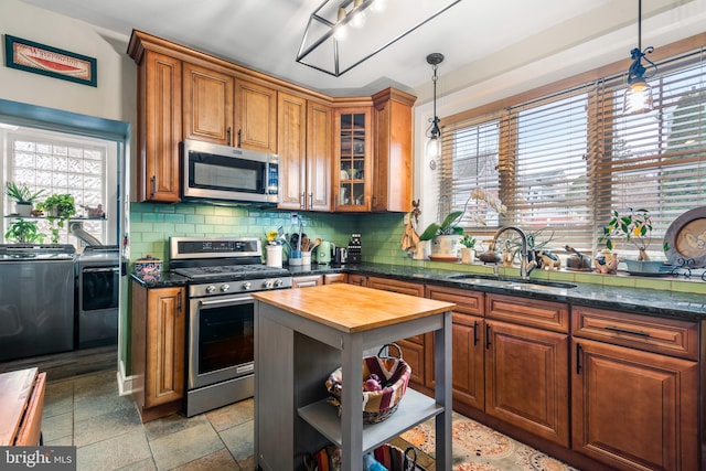 kitchen featuring washing machine and clothes dryer, butcher block countertops, decorative backsplash, a sink, and appliances with stainless steel finishes