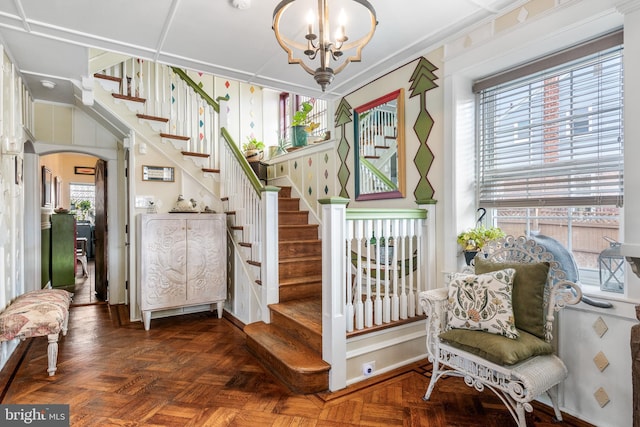 stairs featuring arched walkways, plenty of natural light, and an inviting chandelier