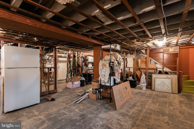 unfinished basement featuring freestanding refrigerator