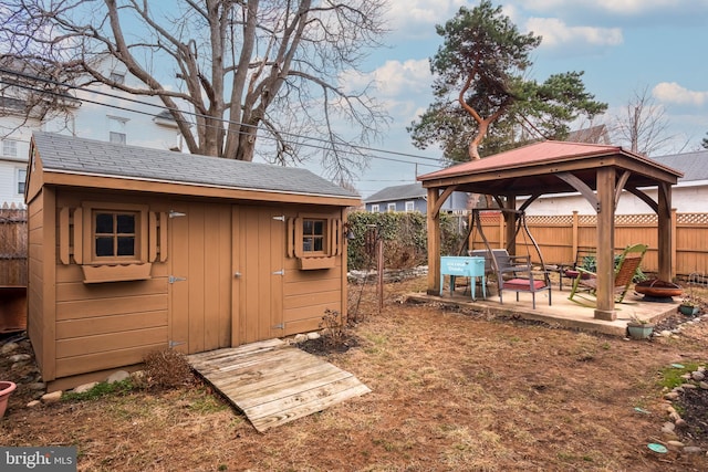 view of yard featuring a gazebo, a fenced backyard, an outdoor structure, a patio area, and a storage unit