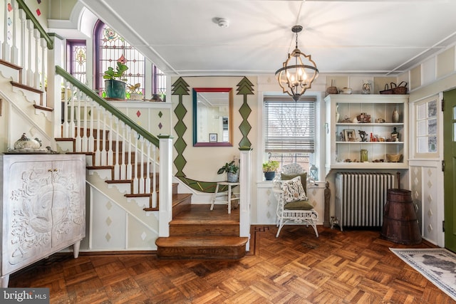 stairs featuring a notable chandelier and radiator