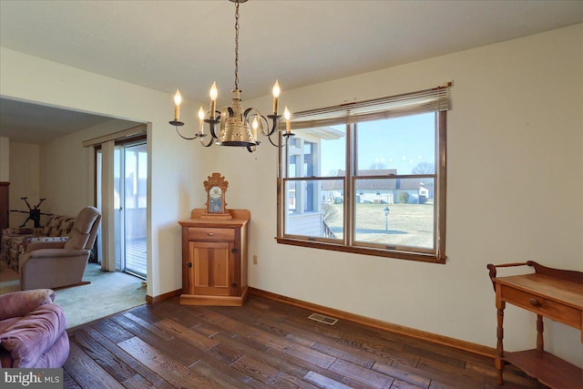 interior space featuring dark wood finished floors, an inviting chandelier, visible vents, and baseboards