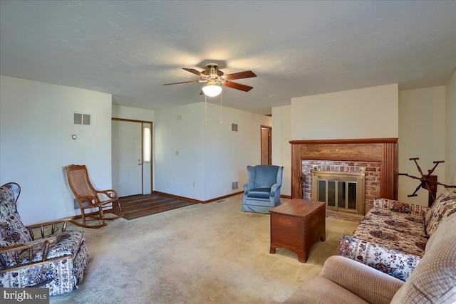 living area featuring visible vents, a textured ceiling, carpet, baseboards, and a brick fireplace