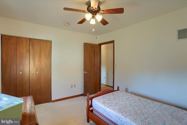 bedroom with visible vents, a ceiling fan, a closet, baseboards, and light colored carpet