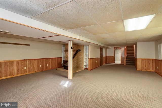 finished basement with stairway, carpet flooring, wood walls, and wainscoting