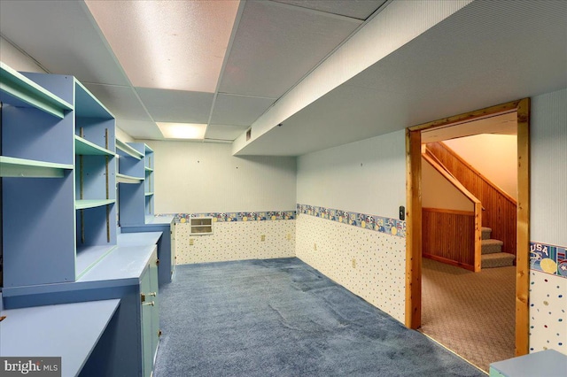 interior space with a drop ceiling, a wainscoted wall, and carpet