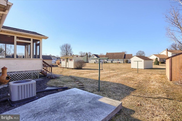 view of yard with an outbuilding, central air condition unit, a storage unit, and a sunroom