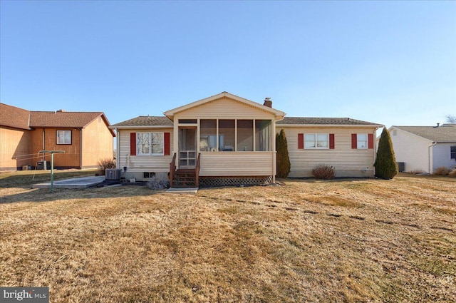 ranch-style house featuring a front lawn, cooling unit, a sunroom, and a chimney