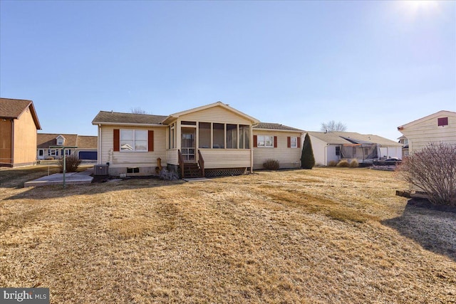 view of front facade featuring a front lawn, central AC unit, and a sunroom