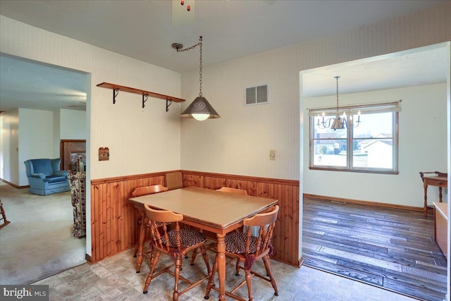 dining area with wallpapered walls, visible vents, a chandelier, and wainscoting