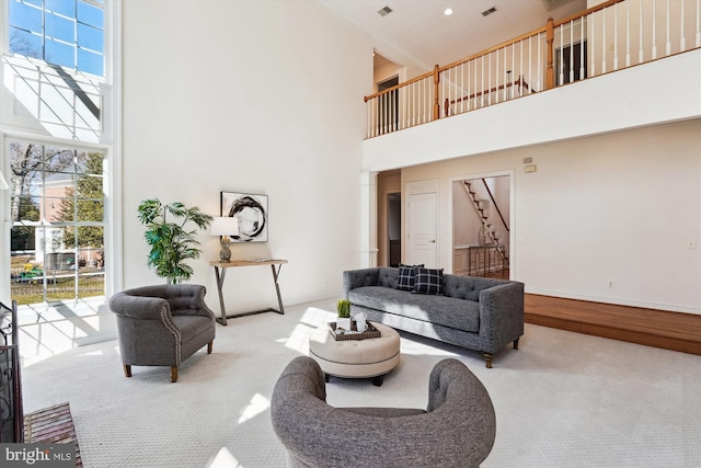 living room with stairs, carpet flooring, baseboards, and a towering ceiling