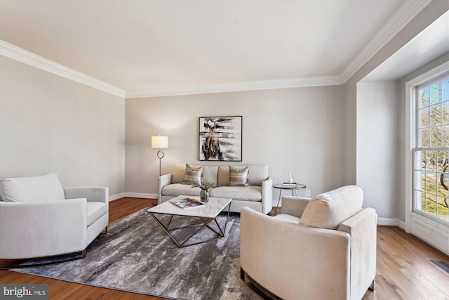 living room featuring crown molding, baseboards, and wood finished floors