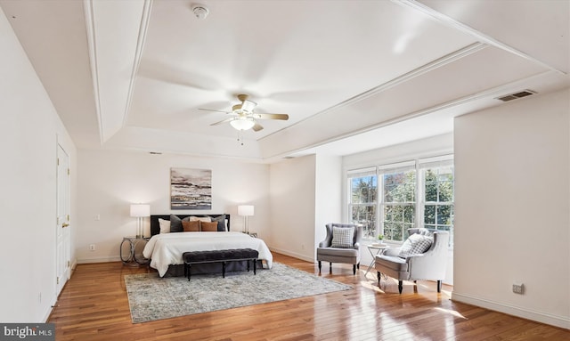 bedroom featuring visible vents, ceiling fan, baseboards, hardwood / wood-style flooring, and a raised ceiling