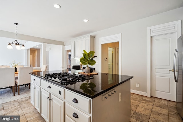 kitchen with ornate columns, dark stone counters, recessed lighting, freestanding refrigerator, and a center island