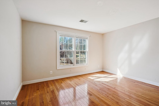 unfurnished room featuring visible vents, baseboards, and hardwood / wood-style floors