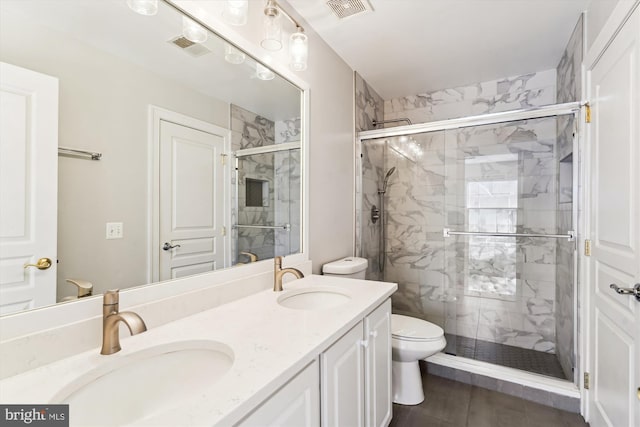 full bath with double vanity, visible vents, a shower stall, and a sink