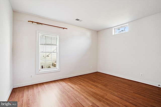 spare room with visible vents, baseboards, and wood finished floors