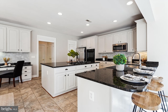 kitchen with a peninsula, recessed lighting, a sink, black appliances, and white cabinets