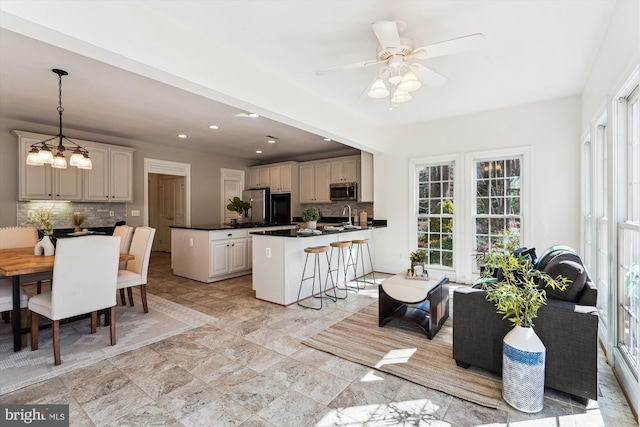 kitchen with a sink, a kitchen breakfast bar, dark countertops, appliances with stainless steel finishes, and a peninsula