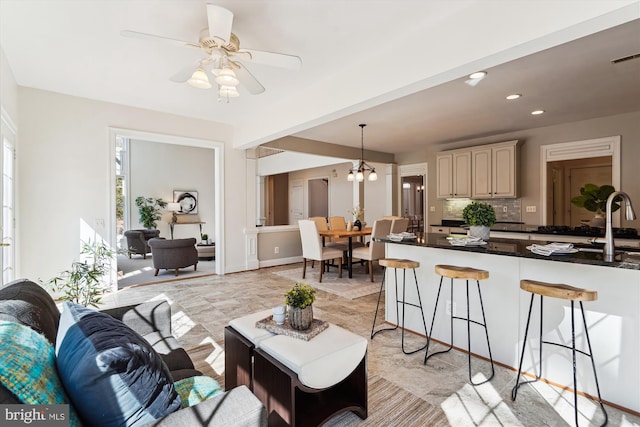 living area featuring recessed lighting and ceiling fan with notable chandelier