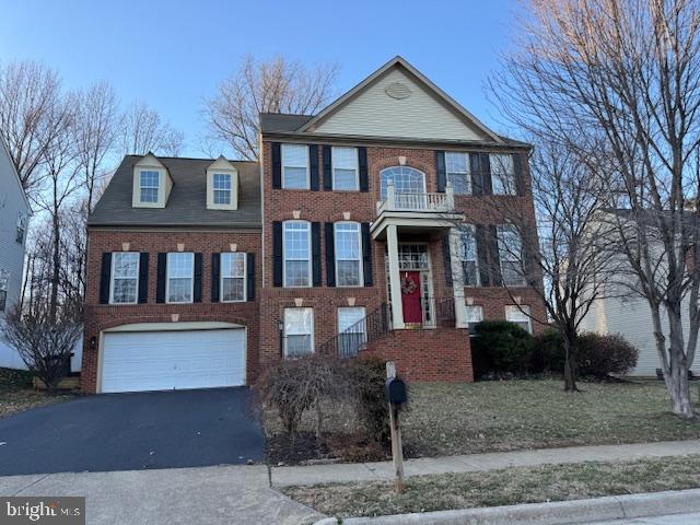 view of front of house with brick siding, an attached garage, aphalt driveway, and a balcony