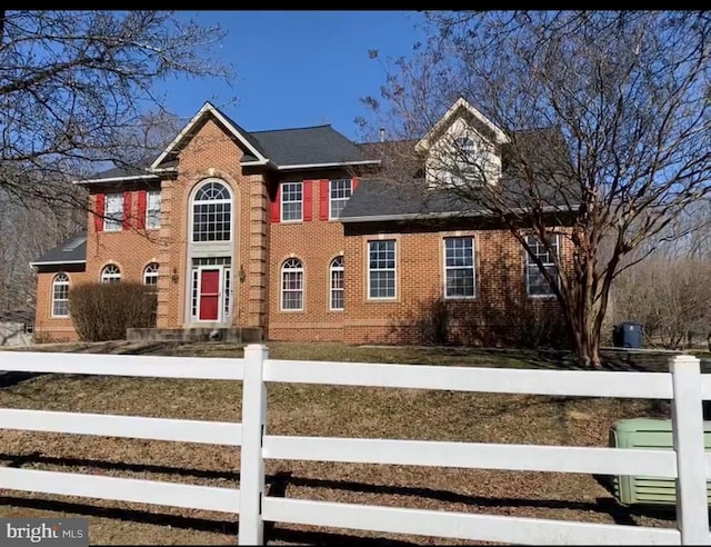 colonial house featuring brick siding and a fenced front yard