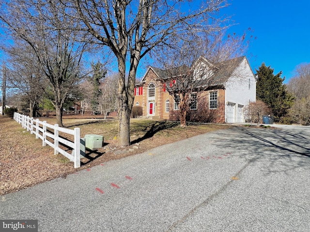 view of front facade with brick siding, an attached garage, aphalt driveway, and fence