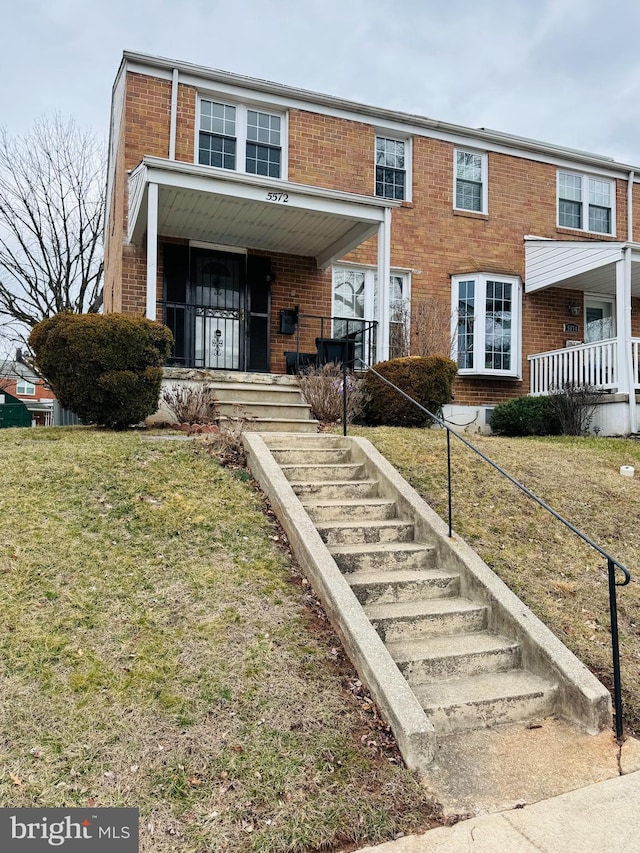 view of property with stairway, brick siding, and covered porch