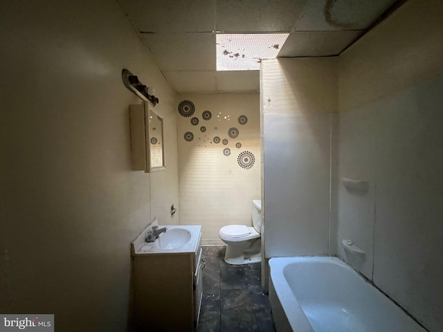 bathroom featuring vanity, toilet, a bathing tub, and a drop ceiling