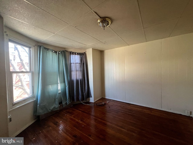 spare room featuring baseboards, a paneled ceiling, and hardwood / wood-style flooring