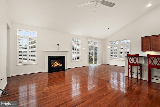 living room featuring ceiling fan, a fireplace with flush hearth, and dark wood finished floors