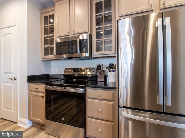 33565 Windswept Dr Unit 10201, Millsboro, DE 19966 - kitchen with dark stone countertops, glass insert cabinets, light wood-type flooring, and stainless steel appliances