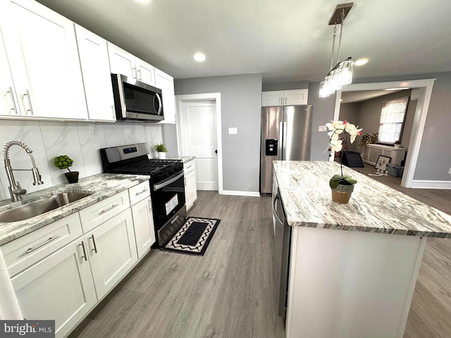 kitchen with backsplash, a kitchen island, appliances with stainless steel finishes, dark wood-style floors, and a sink