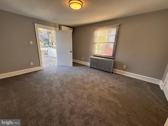 spare room with dark carpet, radiator, and baseboards