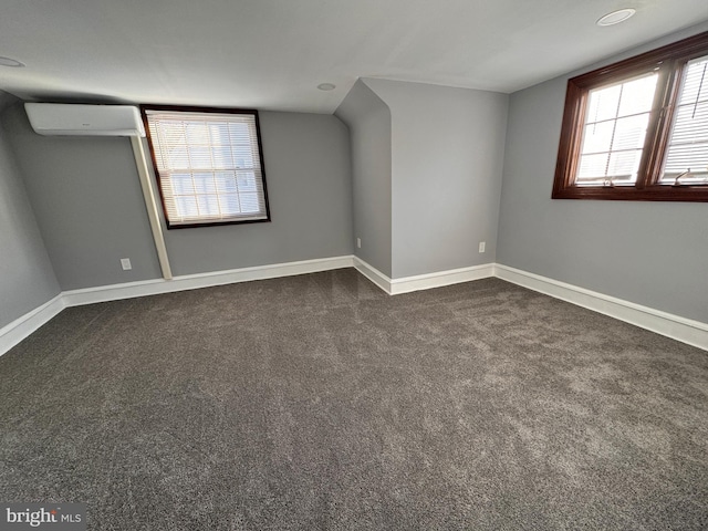 interior space featuring a wall unit AC, baseboards, and dark colored carpet