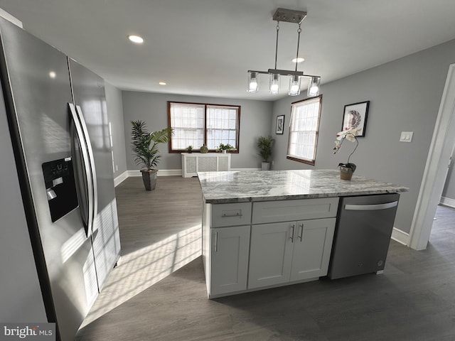 kitchen featuring a center island, dark wood-type flooring, baseboards, decorative light fixtures, and stainless steel appliances