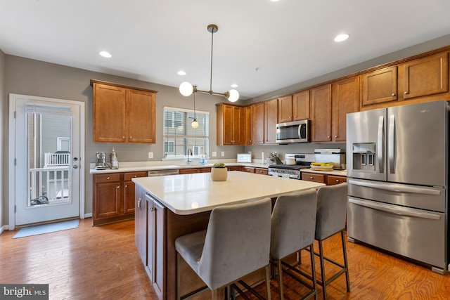 12831 Clarksburg Square Rd, Clarksburg, MD 20871 - kitchen featuring brown cabinetry, a center island, appliances with stainless steel finishes, light countertops, and hanging light fixtures