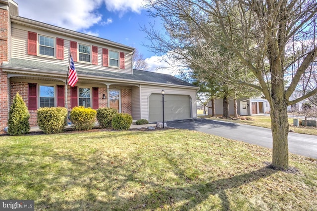 traditional-style house featuring a front yard, brick siding, an attached garage, and driveway