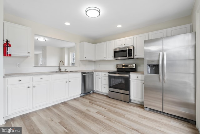 kitchen with a sink, light countertops, white cabinets, and stainless steel appliances