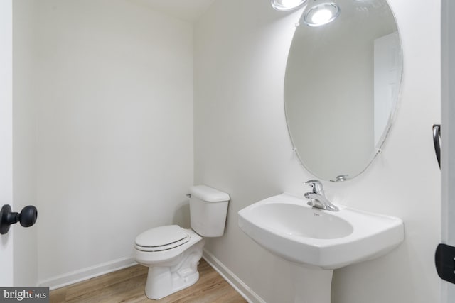 bathroom featuring a sink, toilet, baseboards, and wood finished floors