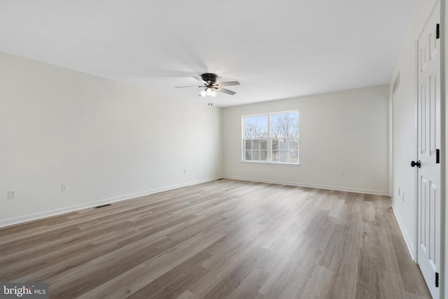 unfurnished room with light wood finished floors, visible vents, a ceiling fan, and baseboards