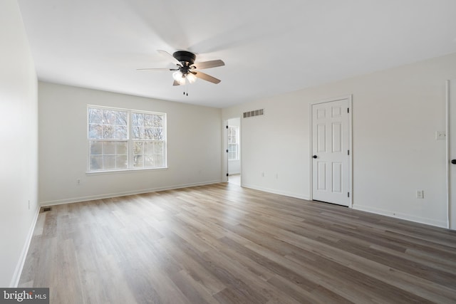 spare room with visible vents, baseboards, wood finished floors, and a ceiling fan