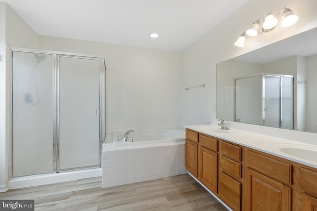 bathroom with a stall shower, a bath, double vanity, and a sink